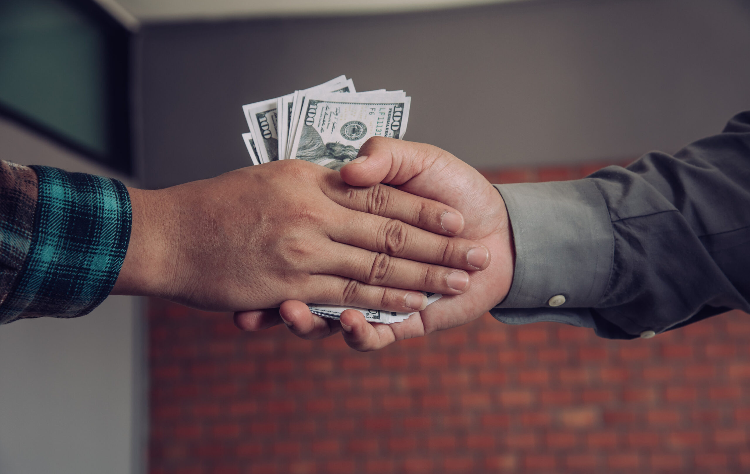 Businessmen handshake with money in hands corruption concept