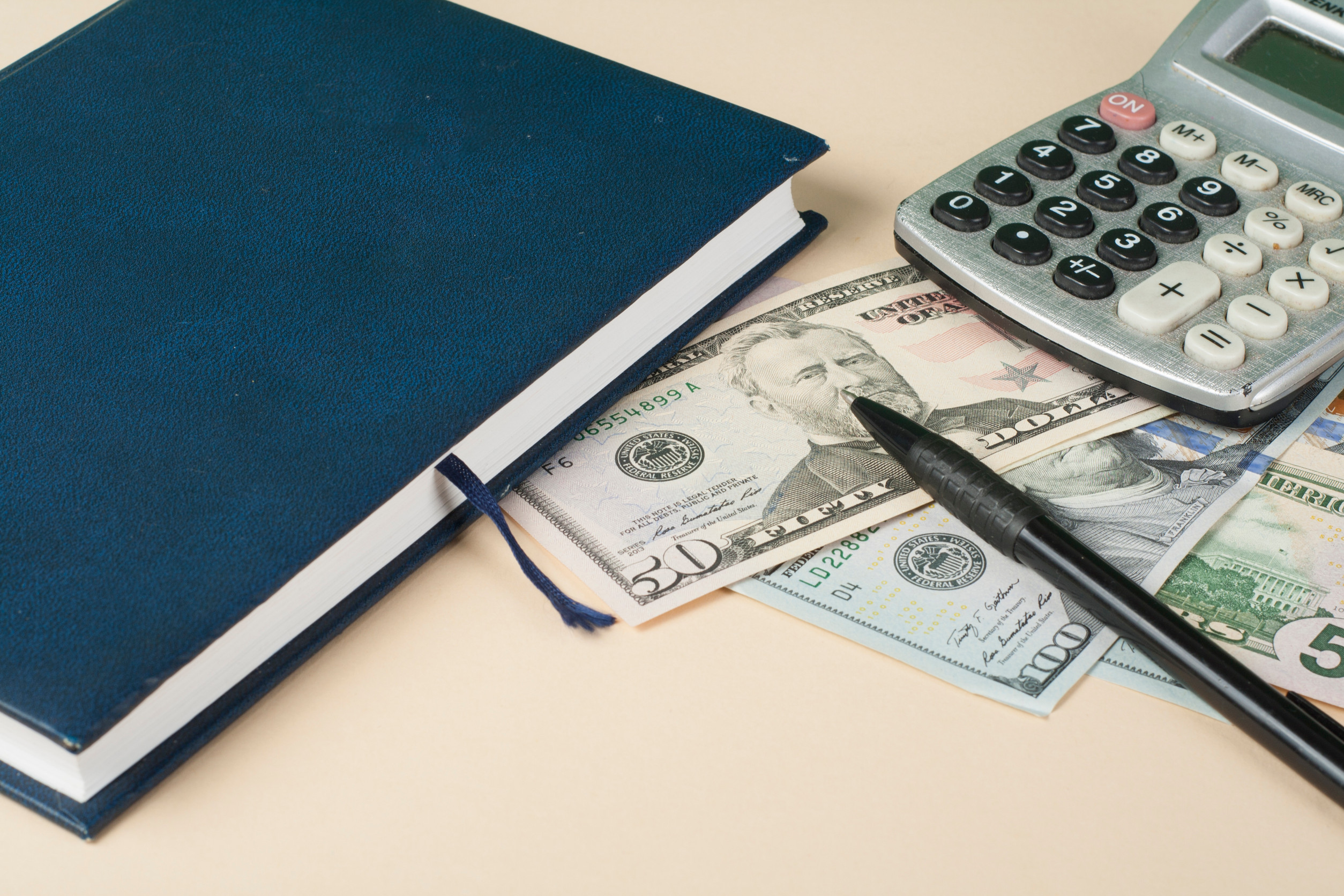 Home savings, budget concept Model house, notepad, pen, calculator and coins on wooden office desk table