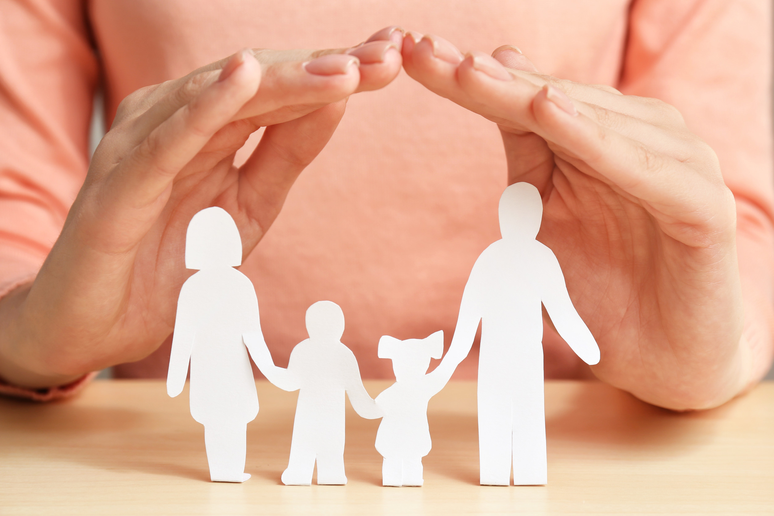 Woman covering paper silhouette of family with hands, closeup Insurance concept