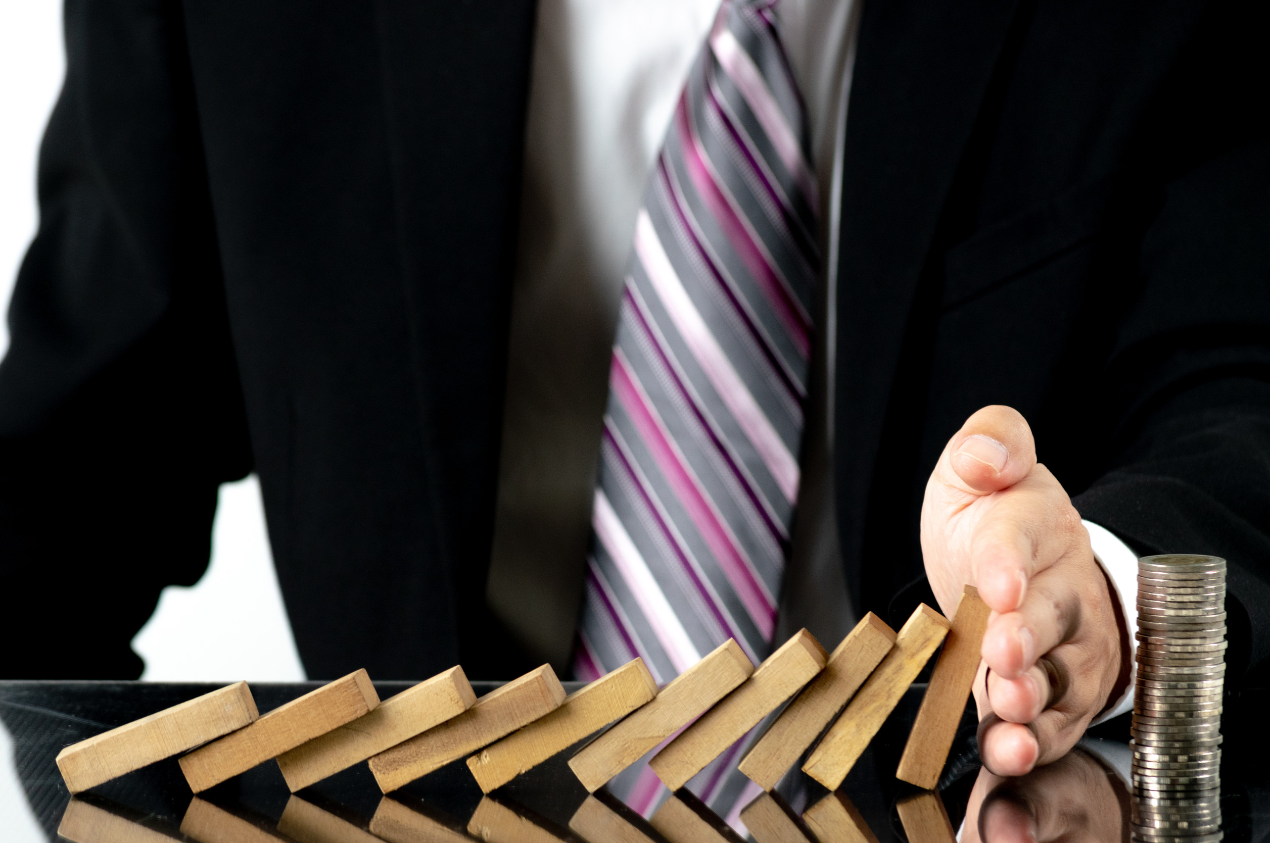 Close up Businessman hand stopping wooden blocks from falling on