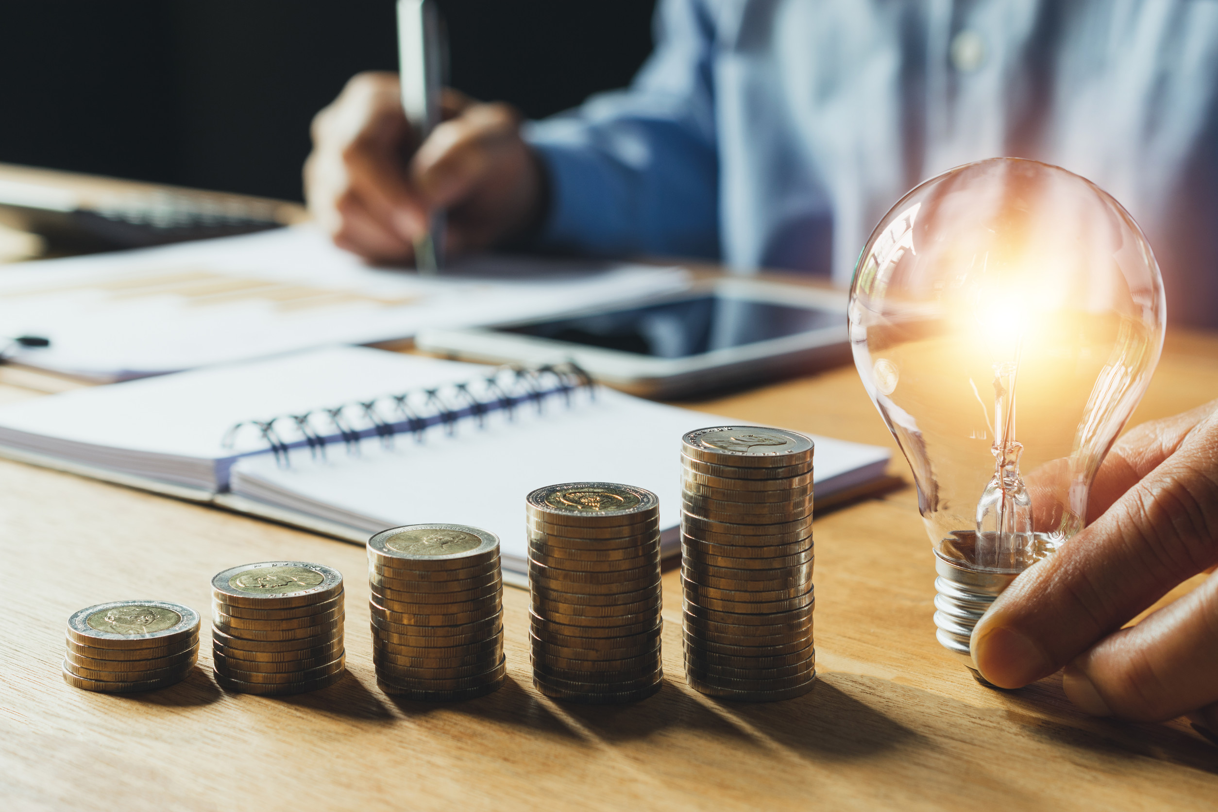 Business man holding light bulb on the desk in office and writin