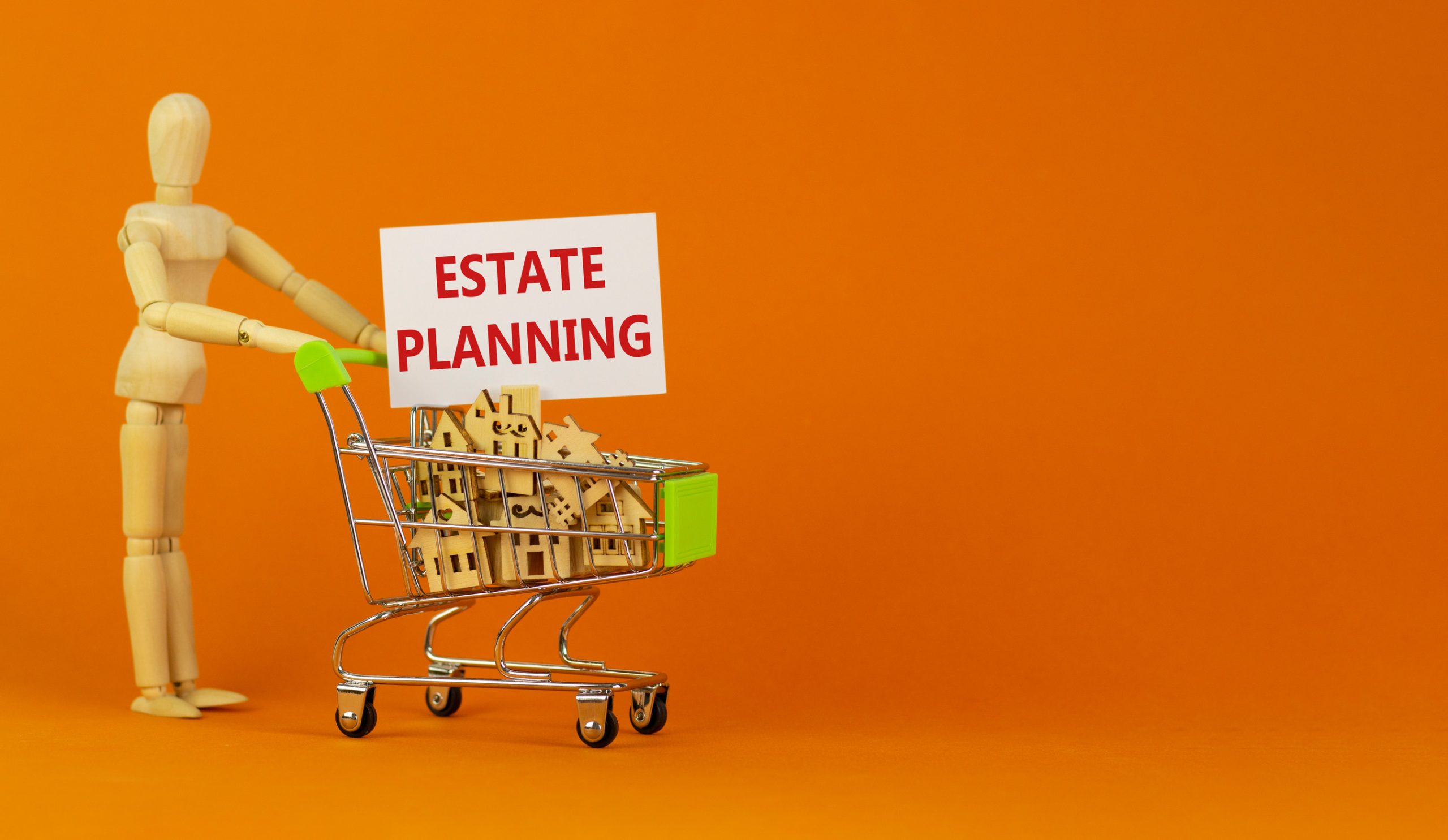 Estate planning symbol Miniature shopping cart with wooden houses, words estate planning Wooden model of human Beautiful orange background, copy space Business and estate planning concept