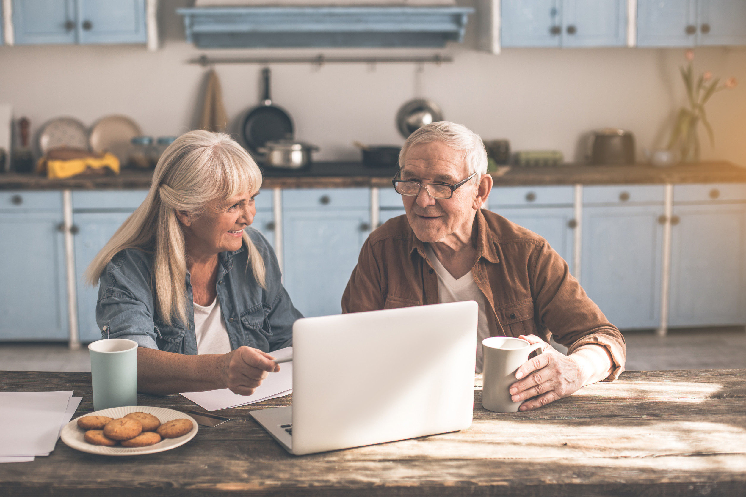 Happy senior married couple solving issues by internet at home