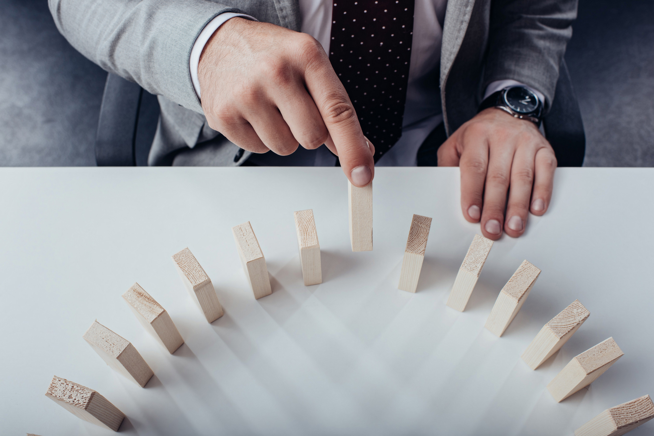 top view of man picking wooden brick from row of blocks on desk