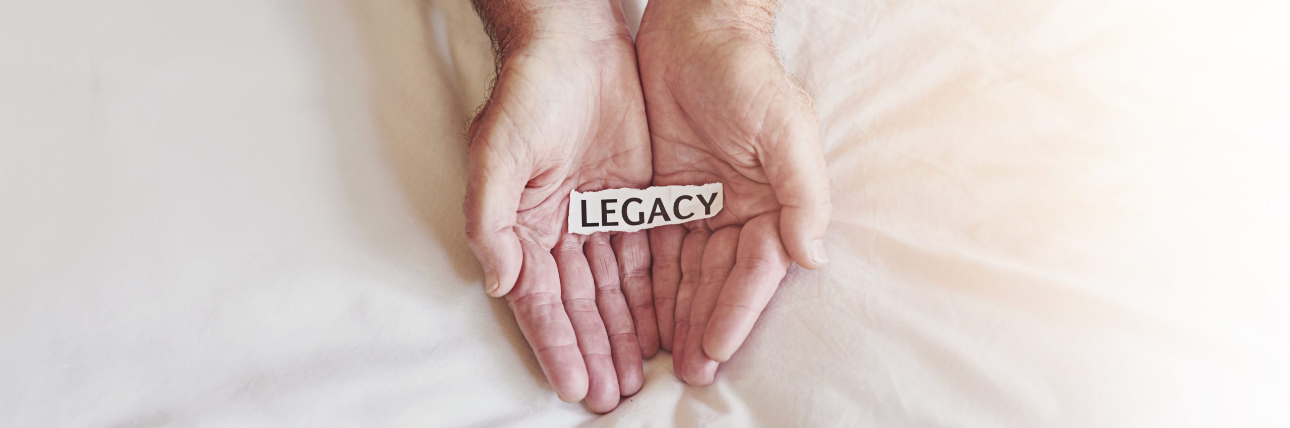 Hands, paper and legacy with text and old person for future, impact and senior responsibility Retirement, history and generations with closeup of words on white background for inheritance or banner